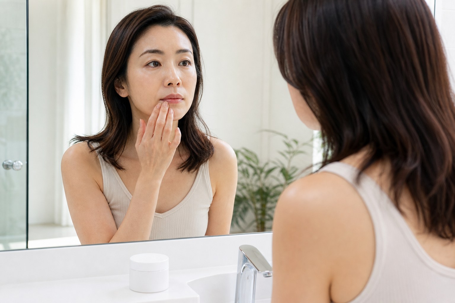 洗面台の鏡の前で目元と口元のかさつきを気にする40代女性